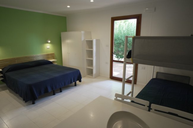 Camera con letto matrimoniale e letto a castello, porta finestra.