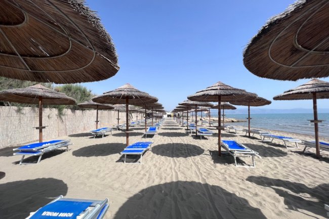 Lettini e ombrelloni su una spiaggia sabbiosa.