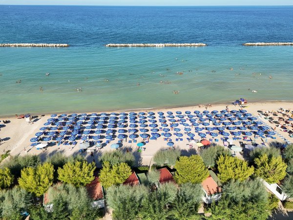 Spiaggia con ombrelloni blu e mare calmo.