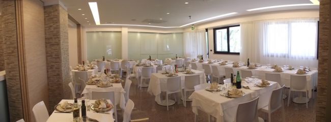 Sala da pranzo elegante, con tavoli apparecchiati con tovaglie bianche e sedie bianche.