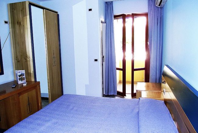 Camera da letto con letto matrimoniale blu e armadio a specchio.