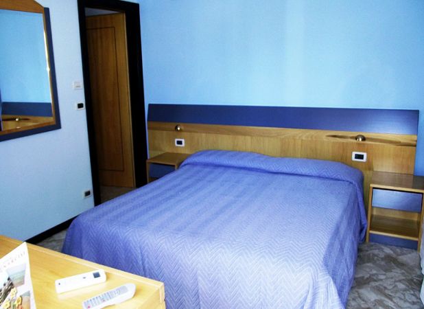 Camera con letto blu, scrivania e parete turchese.