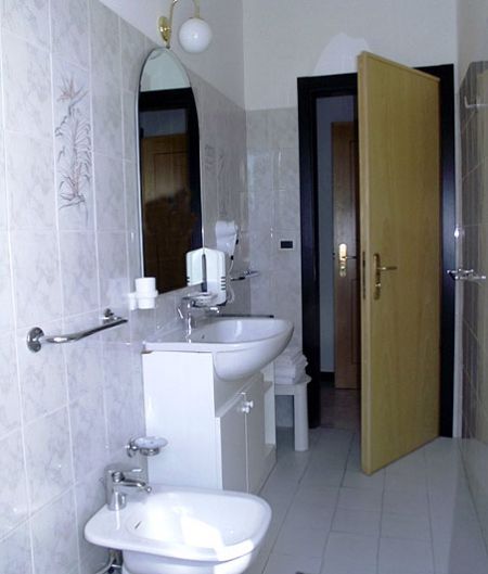 Un bagno con bidet, lavabo e specchio ovale.