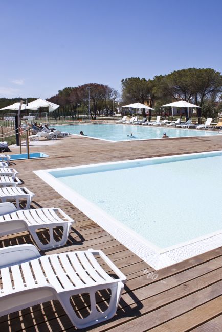 Piscina esterna con lettini e ombrelloni.