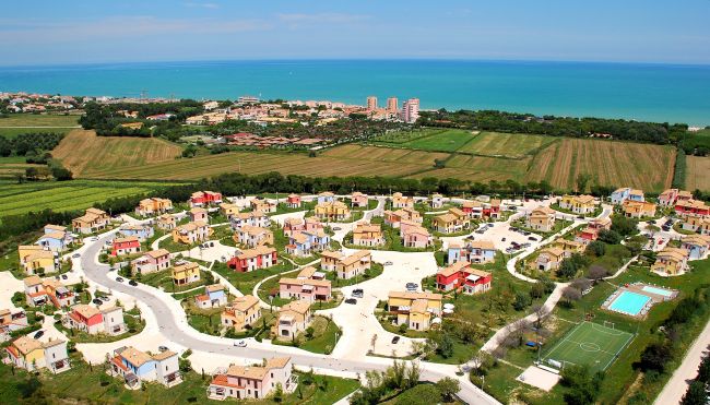 Villaggio turistico con villette colorate vicino al mare.