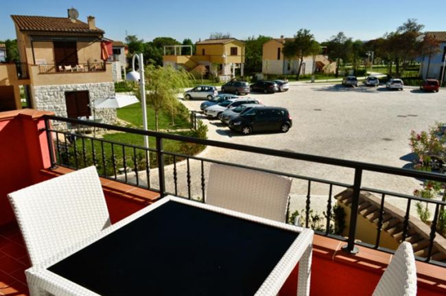 Balcone con tavolo e sedie, vista su parcheggio.
