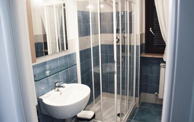 Bagno con lavabo bianco e cabina doccia in vetro.