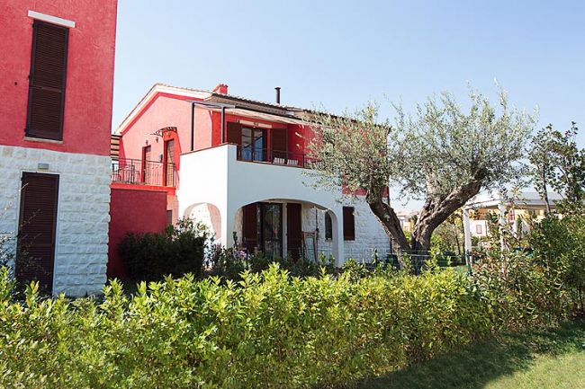 Casa rossa con giardino e alberi.