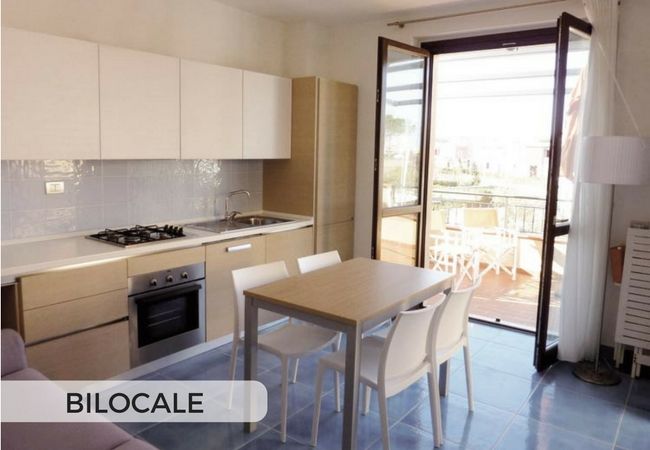 Cucina moderna con tavolo, sedie e porta finestra aperta.