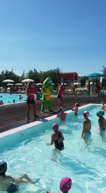 Persone in piscina con mascotte verde.