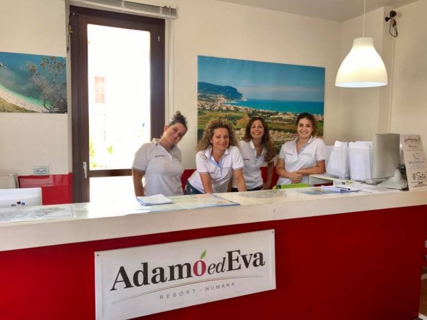 Quattro persone sorridenti al banco della reception.