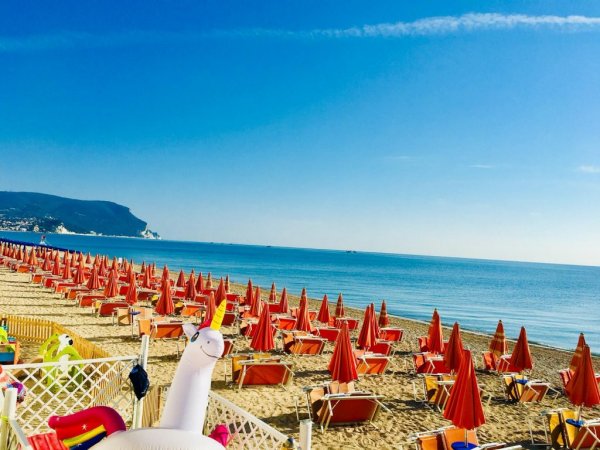 Spiaggia con ombrelloni arancioni e mare.