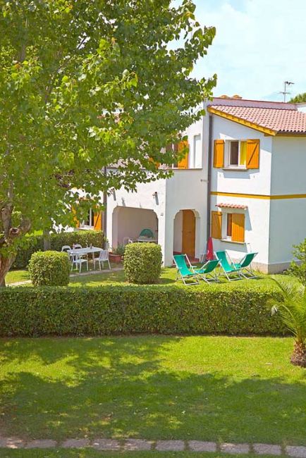 Casa con sedie a sdraio in un giardino verde.