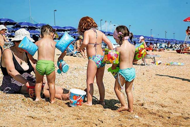 Bambini giocano sulla spiaggia con secchielli.