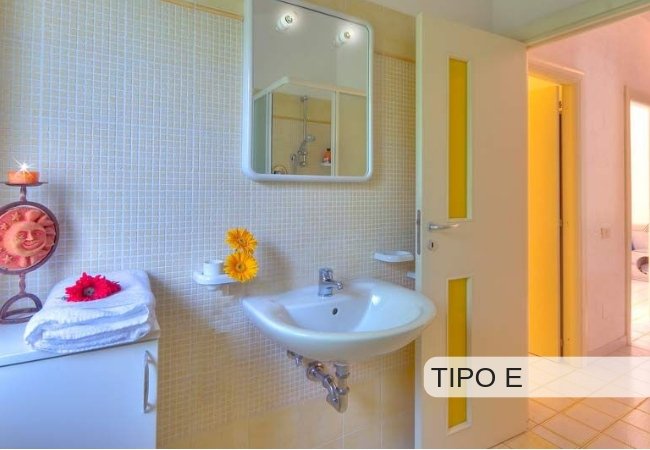 Bagno con lavabo, specchio e asciugamani decorati con fiori.