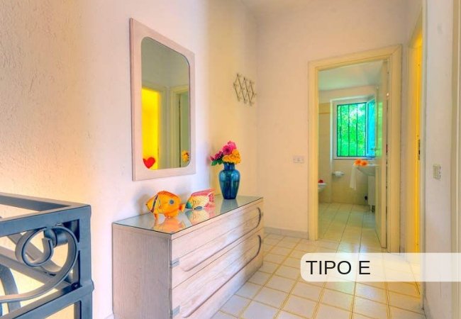 Un corridoio con specchio, cassettiera e fiori colorati.
