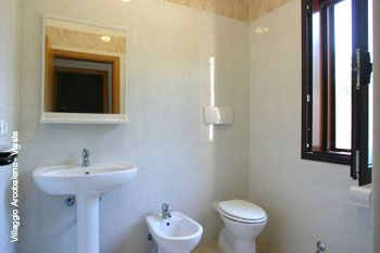 Bagno con lavabo, bidet e wc vicino a una finestra.