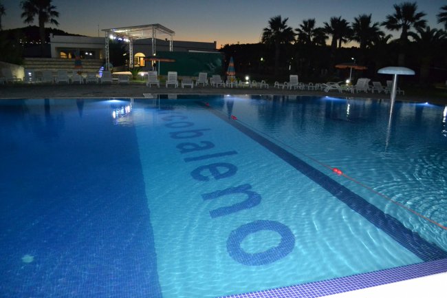 Piscina illuminata di sera con scritta 