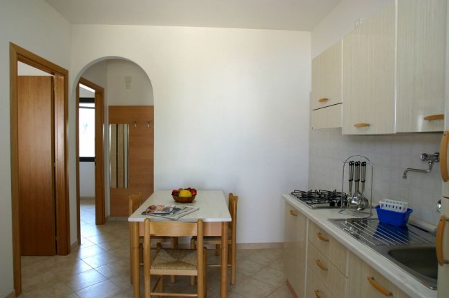 Cucina essenziale con tavolo e sedie.