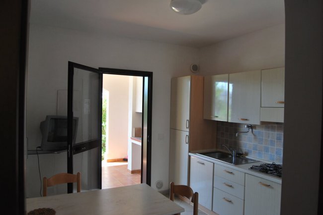 Cucina con tavolo, sedie e porta aperta.