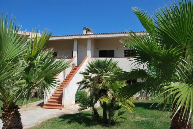 Casa con scala esterna e palme.
