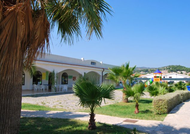 Edificio bianco con portico, palme nel giardino.