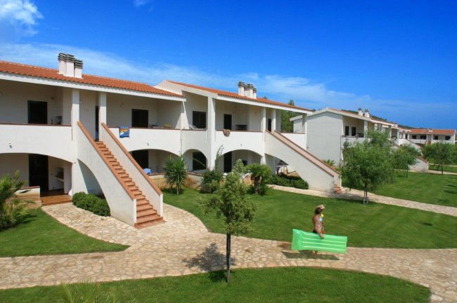 Complessi residenziali bianchi con scale esterne e vialetti in un giardino verde.