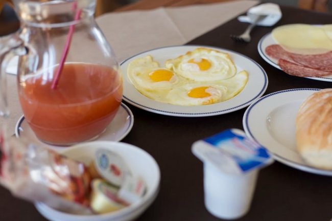 Colazione con uova al tegamino, succo e yogurt.