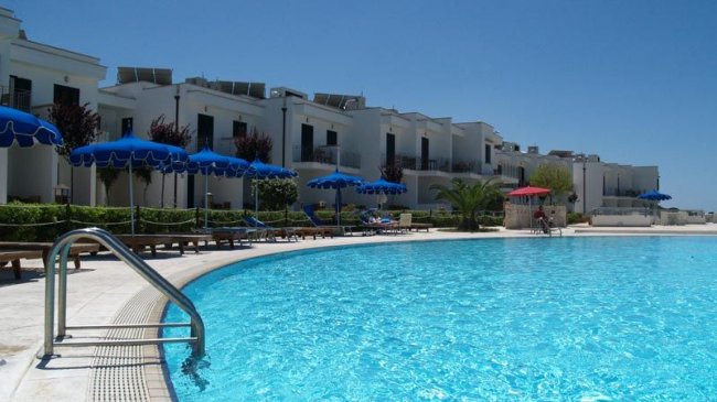 Piscina all'aperto con ombrelloni blu e rossi.