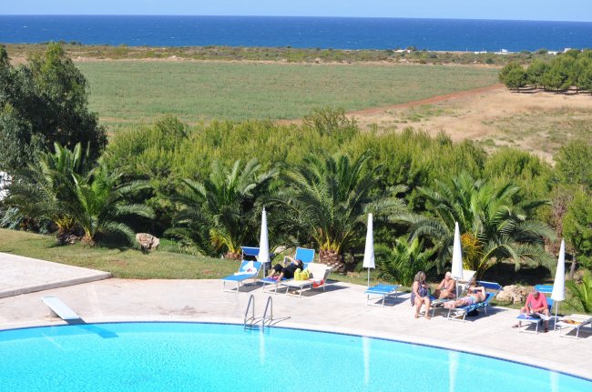 Piscina con lettini e ombrelloni, vista mare e campagna.