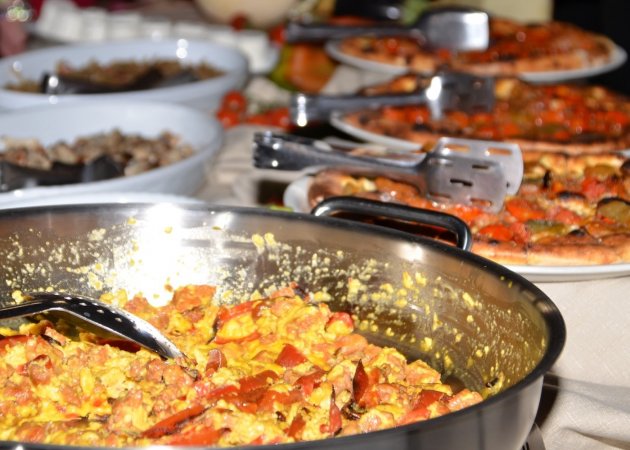 Tavola di cibo vario con padella in primo piano.