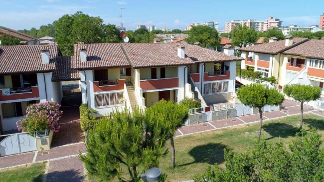 Complesso residenziale con tetti in tegole e alberi verdi.