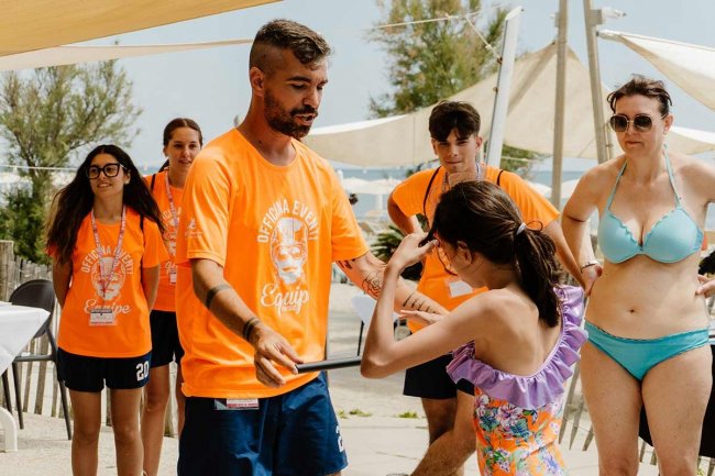 Persone in t-shirt arancioni su una spiaggia.