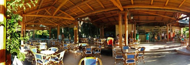 Sala all'aperto con tavoli e sedie in vimini.