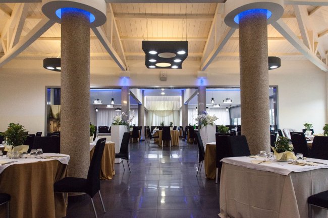 Un elegante ristorante con colonne illuminate e tavoli apparecchiati.