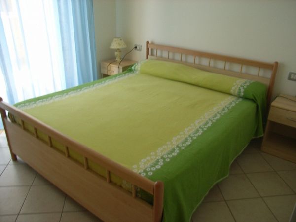 Letto matrimoniale con copriletto verde.