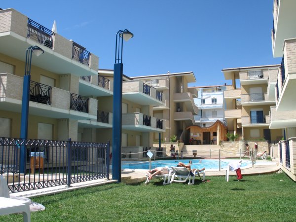 Complesso residenziale con piscina e lettini.