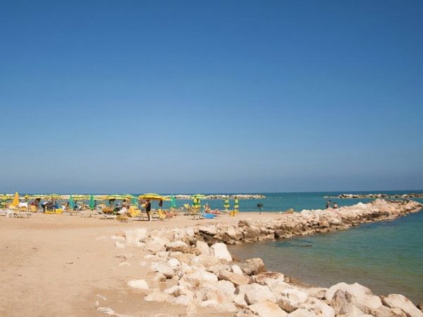 Spiaggia con ombrelloni gialli e verdi.