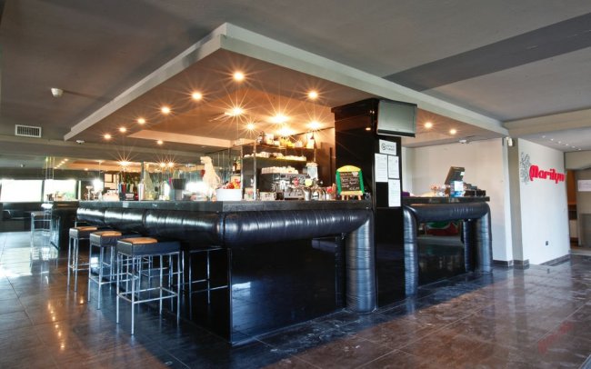 Moderno bar con bancone nero illuminato.