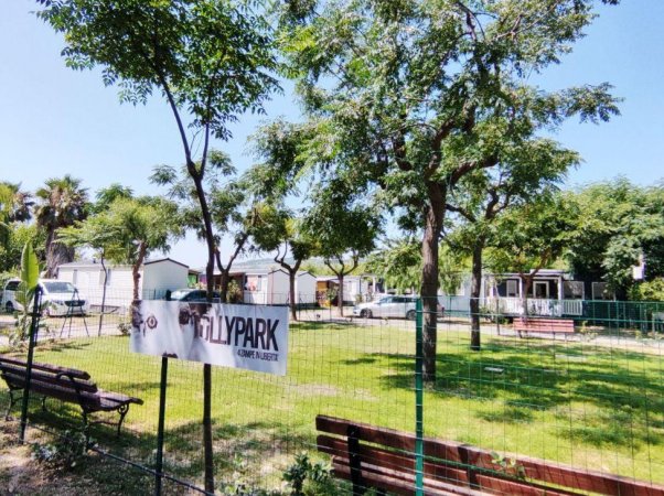 Parco recintato con alberi e panchine.