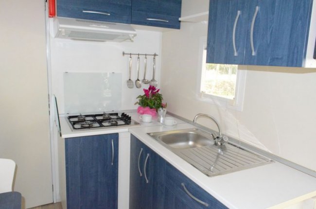 Cucina compatta con mobili blu e lavello.