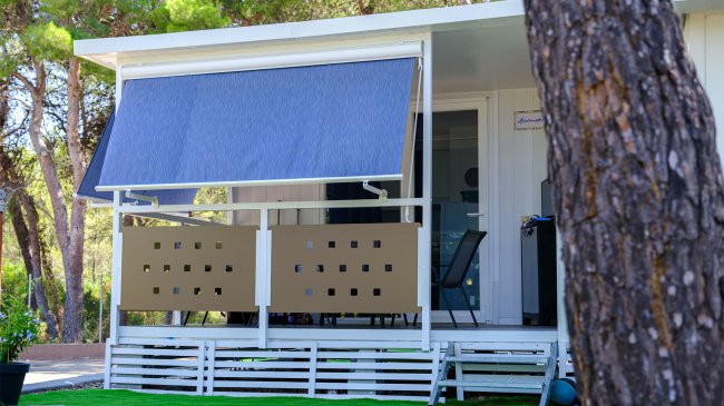 Casetta bianca con veranda e tenda blu.