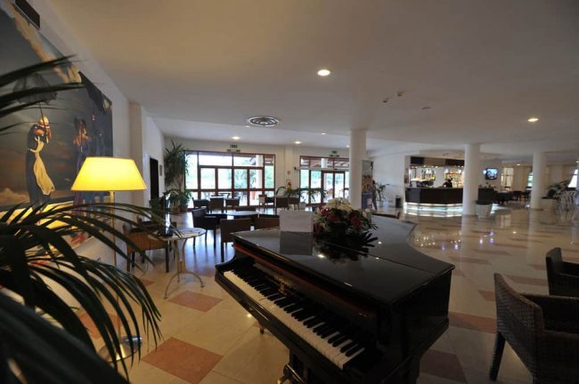 Interno di un hotel con pianoforte e sedie.