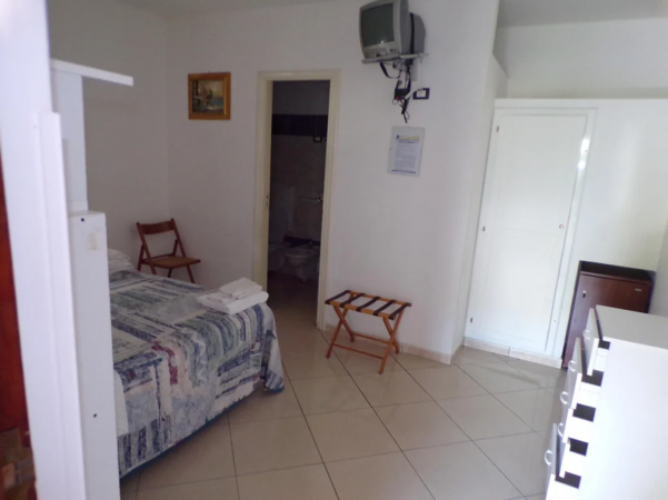 Una camera con un letto matrimoniale, TV a parete e pavimento piastrellato.