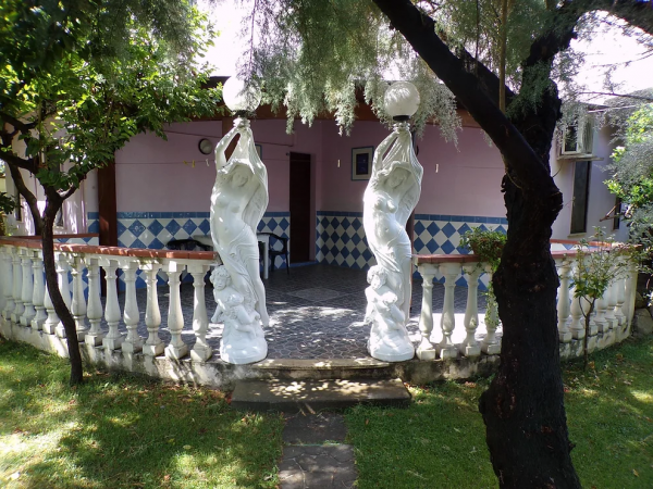 Un giardino con statue bianche e lampade, accanto a un edificio colorato.