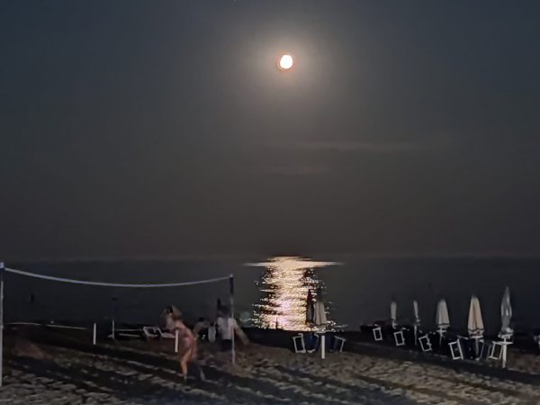 Spiaggia notturna con luna piena e campo da beach volley.