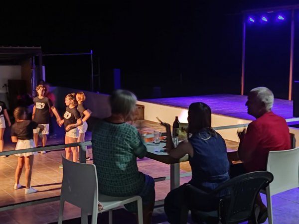 Persone sedute davanti a un palco, guardando bambini ballare.