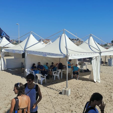 Persone sedute sotto tende bianche su una spiaggia.