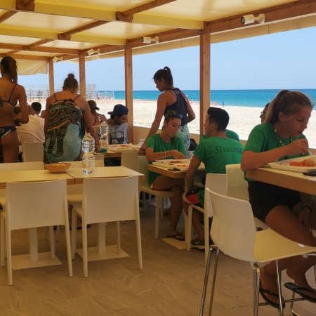 Persone che mangiano in un ristorante all'aperto vicino al mare.