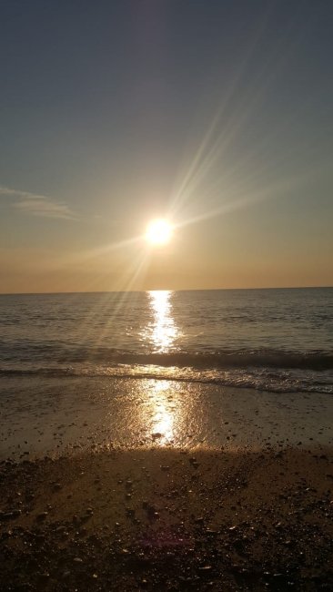 Tramonto sul mare con riflessi sull'acqua.